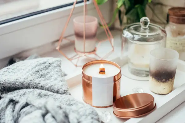 A photo of a candle in a tin with a lit wooden wick