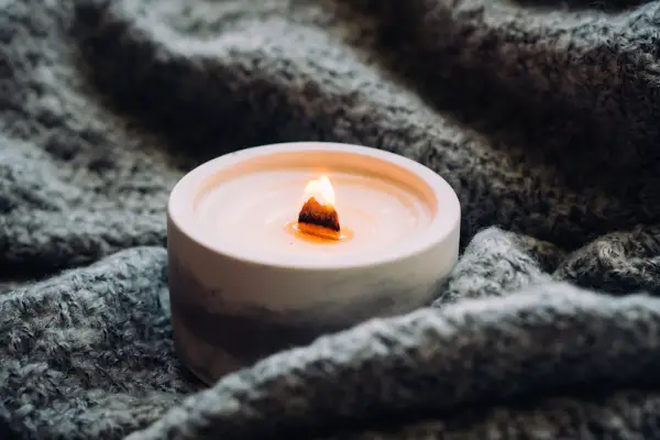 A close up photo of a candle with a wooden wick