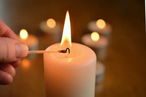 A photo of a candle being lit with a long match