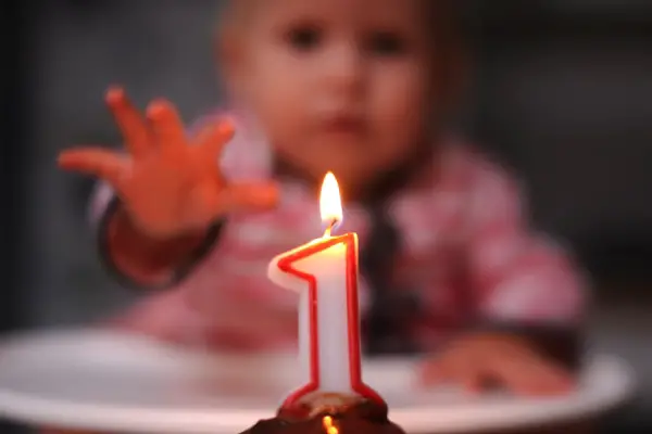 A photo of a baby trying to grab a lit candle
