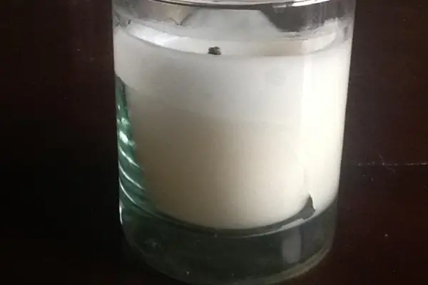 A photo of a white candle with a wet spot on the side