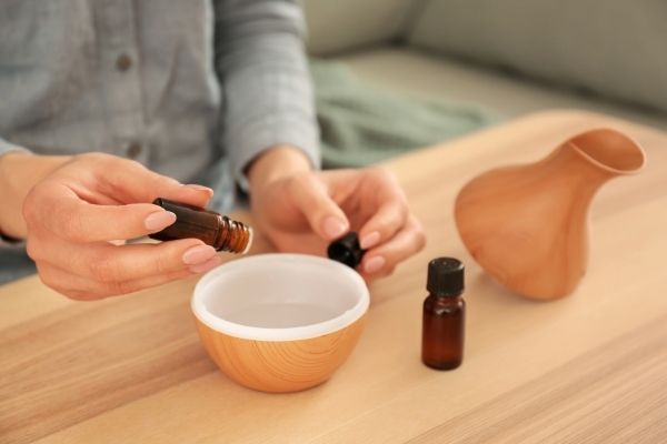 A photo showing drops of essential oil being placed into a diffuser