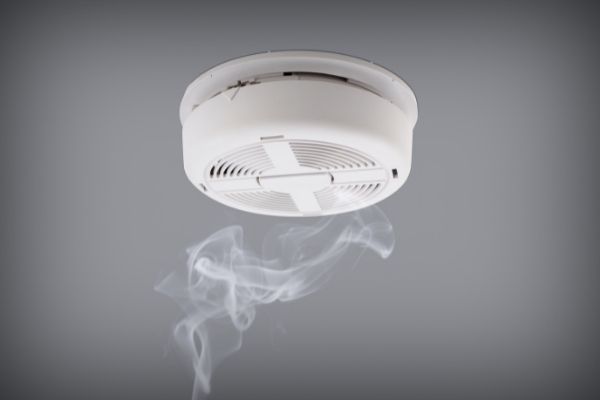A photo of a smoke alarm with candle smoke below it