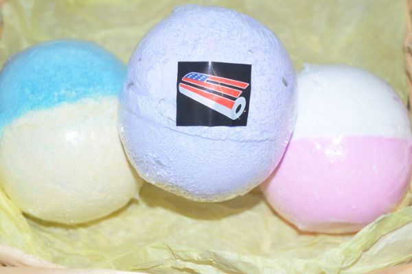 A photo of 3 bath bombs that still have the plastic wrapper on them
